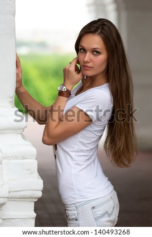 Attractive young woman leaning on white column