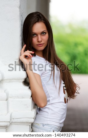 Attractive young woman leaning on white column