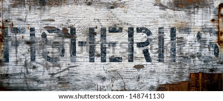 A Grungy, Weathered Sign At A Dock Saying Fisheries