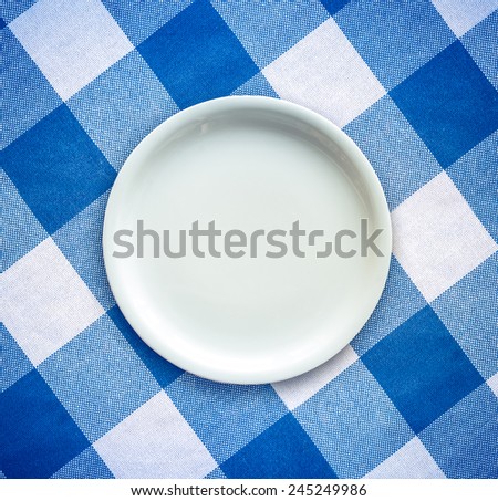 Retro Filtered Empty White Plate On A Checked Table Cloth