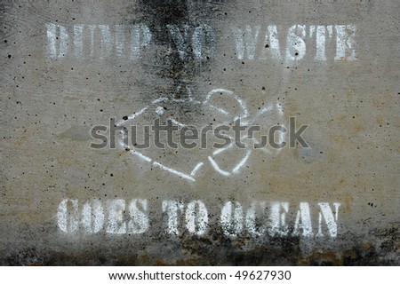 Weathered \'dump no waste goes to ocean\' warning sign on concrete