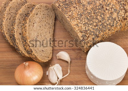 wholemeal bread on wooden cutting board bread with  white cheese, onion and garlic