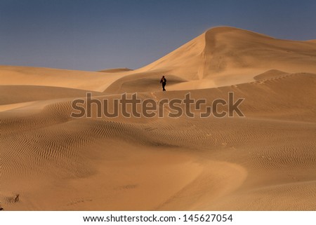 a woman walking on the dunes of the desert