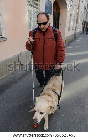 St. Petersburg, Russia - May 29, 2012: A blind man of 50 years during training walking around the city with the help of a guide dog breed Labrador on the main street.