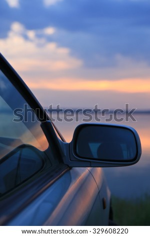 car on the river bank against the evening sky