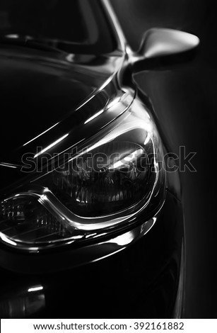 black car in patches of light on black background