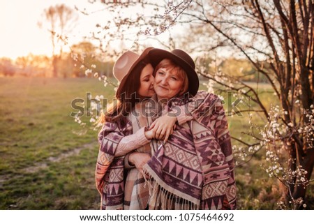Middle-aged mother and her adult daughter hugging in blooming garden. Mother\'s day concept. Family values