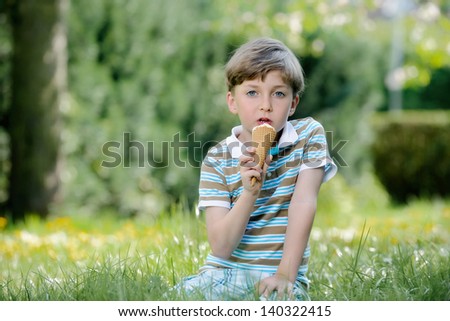 Happy boys eat ice cream on a grass outdoors in spring park