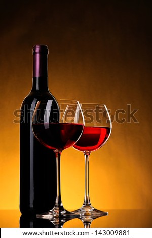 bottle of wine and two glasses wine on yellow background