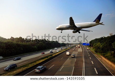 Jet aircraft on landing approach flying low over dual carriageway