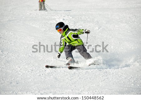The boy in a green jacket on skis in mountains