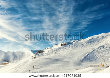 skier near a snow cannon which is making powder snow