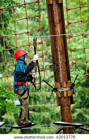 adventure climbing high wire park - people on course in mountain helmet and safety equipment