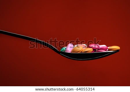 spoon full with colorful medicament pills