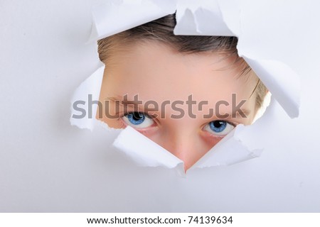 observing eyes of a child in the hole of white paper