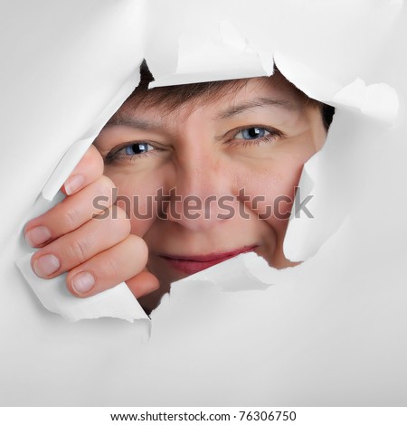 observing eyes of a woman in the hole of white paper