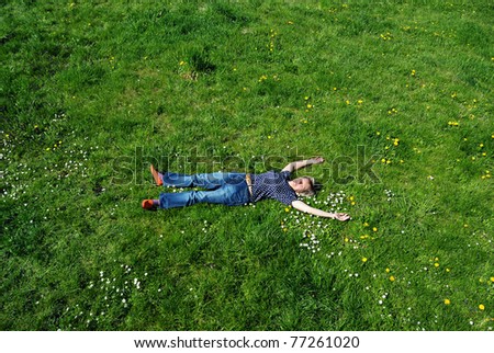 Beautiful young woman laying on the green grass and dreaming