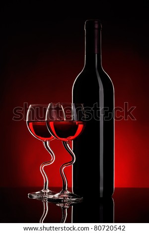 still-life arrangement: bottle of wine and two glasses wine on red background