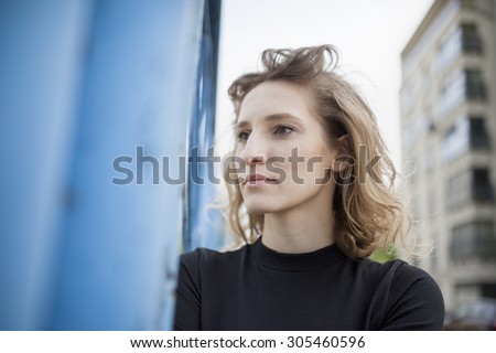 Natural Beauty. Beautiful woman with a serious expression on her face smiling and looking straight ahead with a view of industrial view in the background