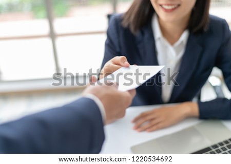 Young Asian business woman receiving salary or bonus money from boss or manager at office happily.