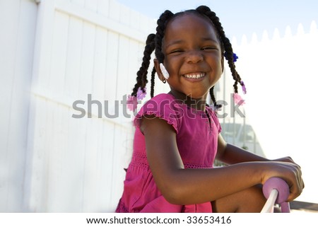 An adorable little african american girl in a pink shirt