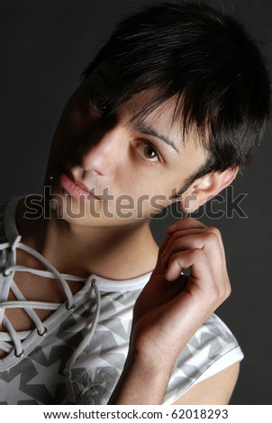 Boy touching his ear piercing on black background