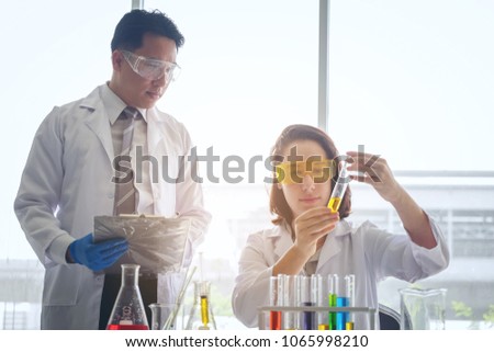 Young female scientist standing with techer in lab worker making medical research in modern laboratory. Scientist holding documents folder with analysis results.