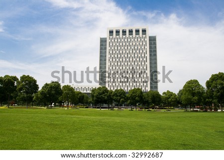 a tall building surrounded by greenbelt and green trees in shanghai university of engineering science