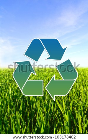 Meadow with green grass and blue sky with clouds and Conceptual recycling sign