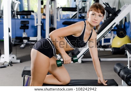 The woman with dumbbells in sports club