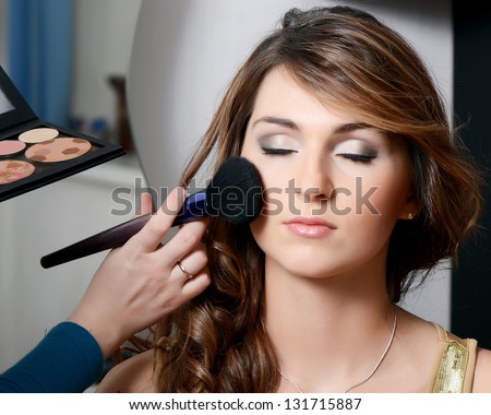 Beautiful girl put the makeup on the face