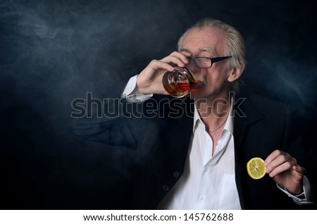 The elderly man with a glass of whisky on a black background