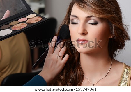 Beautiful girl put the makeup on the face