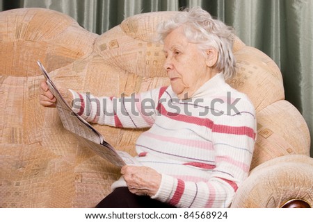 The elderly woman reads on a sofa