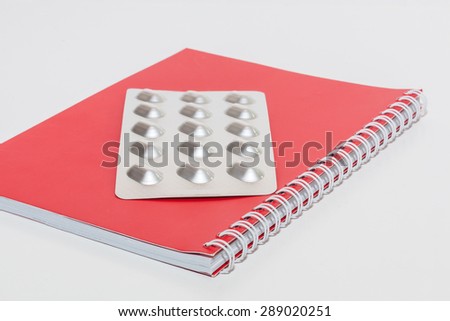 Tablets and Red spiral notebook on white background