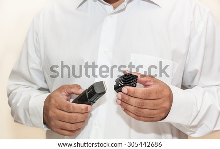 A man in white long sleve shirt holding hair trimmer