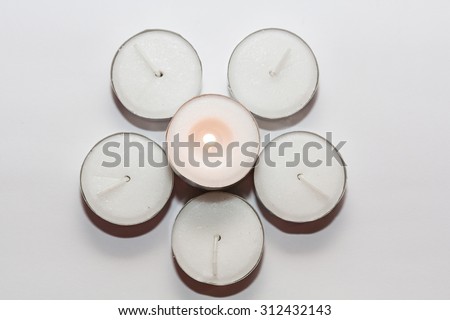 Round candles arranged in circles with center candle lit top view