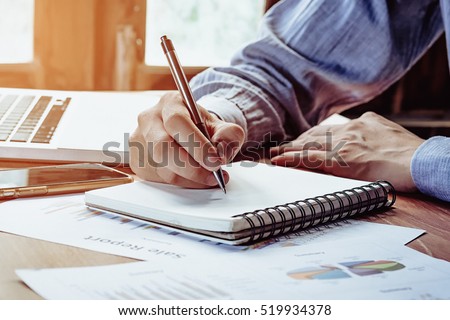 Businessman hands with pen writing notebook  on office desk table close up. Business concept.