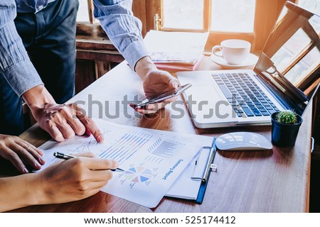 Two colleagues discussing data with smart phone and new modern computer laptop on desk table. Close up business team concept.