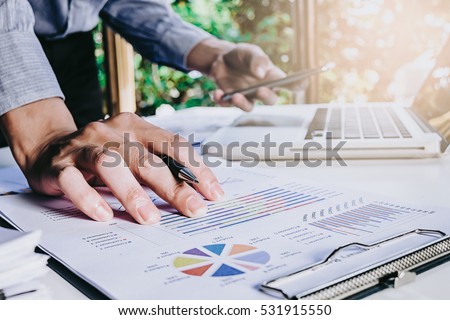 Businessman hand working  with business graph or analysis chart and using smart phone .Close up with sun flare.Business analysis and strategy concept.