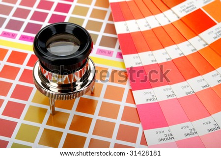 Lupe and a color guide on printed color chart (red, orange and yellow)