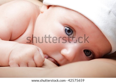 stock photo Child in a white hat sucking mother's breast