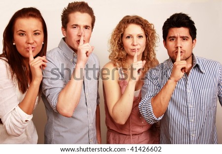 Young men and women with finger on lips as if sharing a secret.