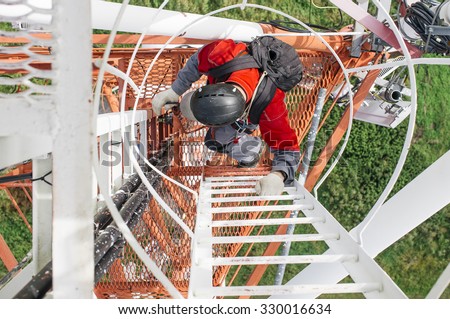 Industrial climber climbs the telecommunications tower. Industrial climber with a backpack on his shoulders climbs the telecommunication tower, top view