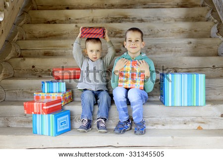 children receive gifts. two happy brother sitting on the stairs with a pile of gifts