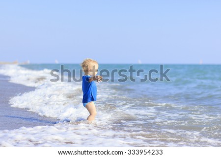 baby playing on the waves of the sea. baby delighted: he first sees the sea and the bold move to play in the waves, retro style