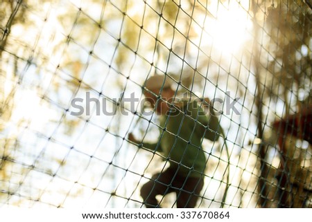 practice nets playground. a boy plays in the Playground shielded with a protective safety net. blurred background and blurred motion due to the concept