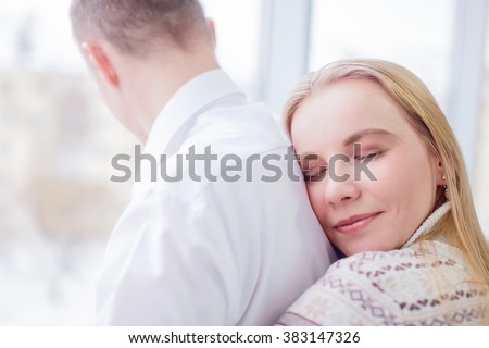 happy woman embracing man from back. beautiful blonde girl closing her eyes and smiling happily hugging a man from behind. concept of close connection, honey and hug