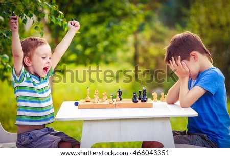 vivid emotions after the game of chess. two young chess players outdoors. boy rejoices won a game of chess. sad opponent covered his face, and upset losing