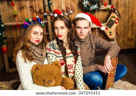 The guy with two girls in a room with wooden walls, gifts and Christmas decorations. New Year concept